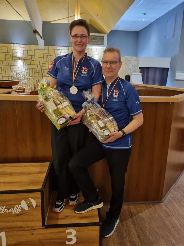 Eine Frau und ein Mann in blauer Bowlingkleidung stehen auf einem Podest