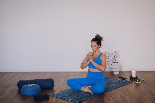 Eine Frau in Sportkleidung macht eine Yoga-Übung auf einer Sportmatte