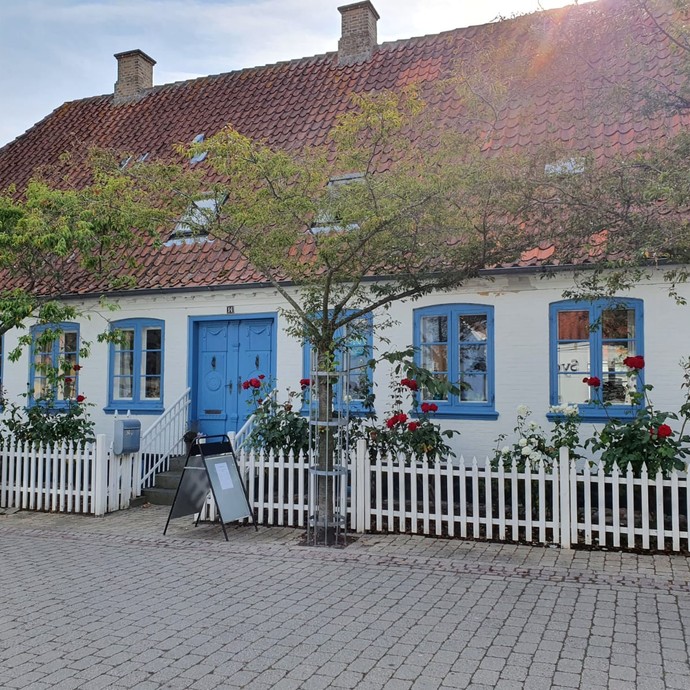 Blick auf ein Haus, davvor Tische mit Kaffee und Kuchen (vergrößerte Bildansicht wird geöffnet)