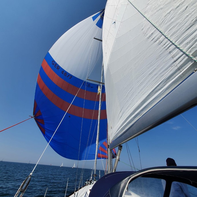 Ein vom Wind aufgeblähtes, blau-weißes Segel (vergrößerte Bildansicht wird geöffnet)