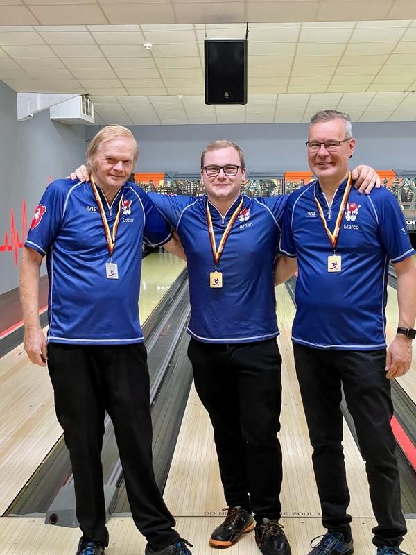 Drei Männer in blauer Bowlingkleidung stehen auf einem Podest